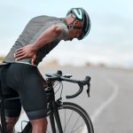 Man feeling pains from oblique muscle injury while standing with bike