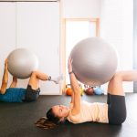 Couples doing ball squeeze exercise in living room