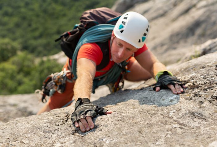man engaging in dangerous sports climbing mountain