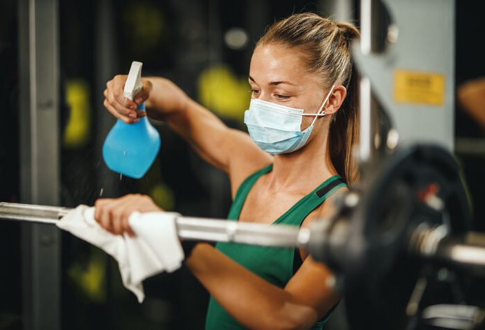 Hygiene in Sports - woman cleaning bar bell