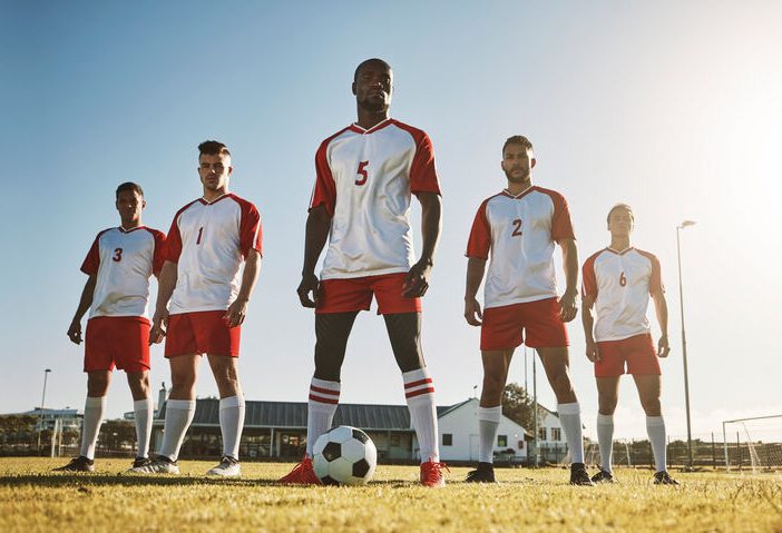 players in a soccer team standing tall with a ball at their feet